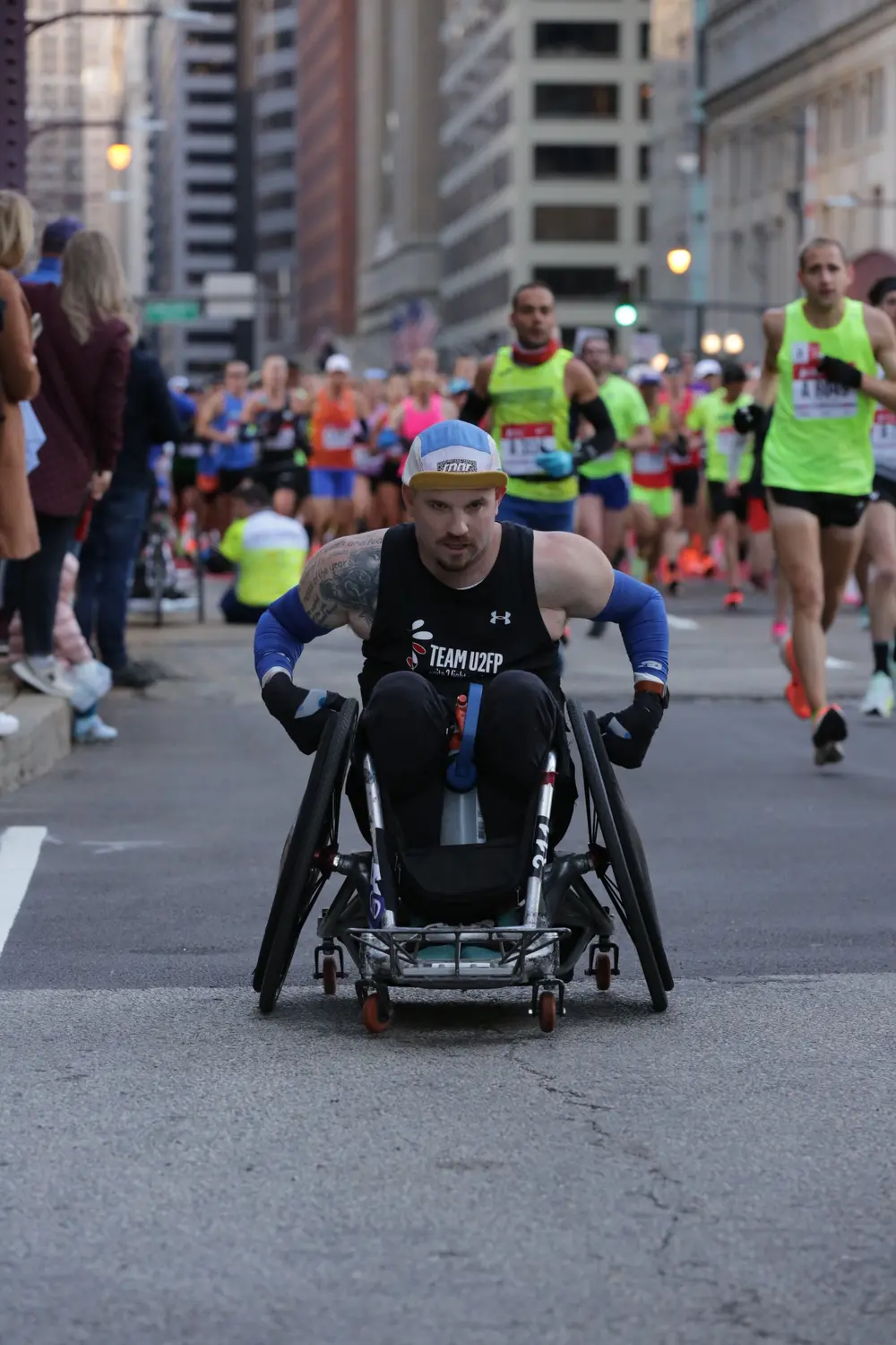 Thomas Cloyd pushing his quad rugby chair at the front of a pack of runners in downtown Chicago